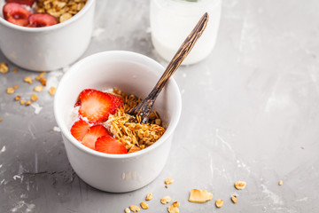 Homemade granola with yogurt and berries in small white bowls. Healthy food concept.