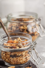 Homemade oat granola in glass jars, macro. Healthy food concept.