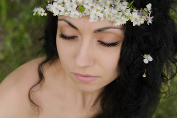 Beautiful young woman with spring flower wreath on her curly black hair