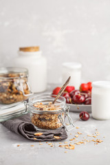 Homemade oat granola in glass jars with cherry and yogurt. Healthy food concept.