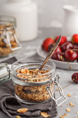 Homemade oat granola in glass jars with cherry and milk. Healthy food concept.