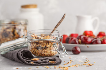 Homemade oat granola in glass jars with cherry and milk. Healthy food concept.