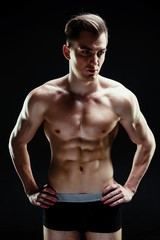 Fototapeta premium Handsome sporty young man in underwear posing on dark background