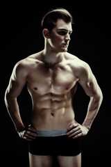 Fototapeta premium Handsome sporty young man in underwear posing on dark background