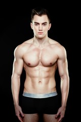 Fototapeta na wymiar Handsome sporty young man in underwear posing on dark background