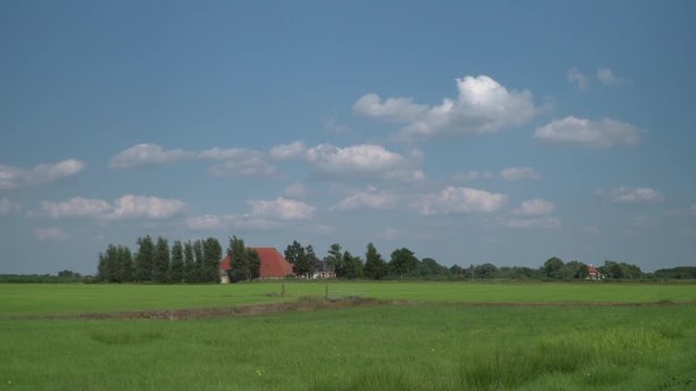 Farm house in Friesland with meadows, blue sky and clouds - time lapse footage
