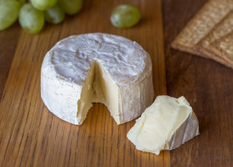 Camembert cheese and slice on wooden board