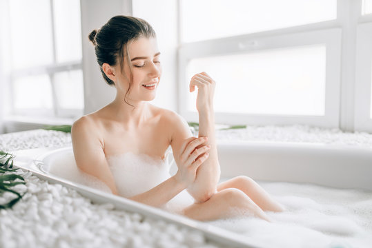 Sexy woman rubs the body with foam in the bath