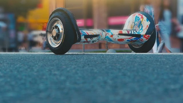 A gyroboard on a busy street. A man approaches a standing gyroboard, gets on it and leaves