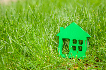 Eco house in nature. Symbol of  house on green grass in summer. Copy space 