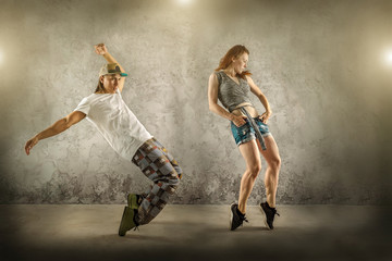 Hip Hop dancer in dynamic action jump on the grunge grey background