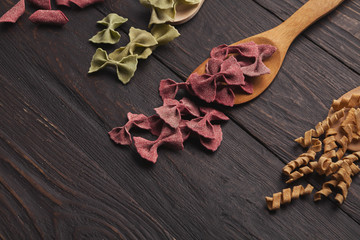 Assorted colorful pasta on wooden table, copy space