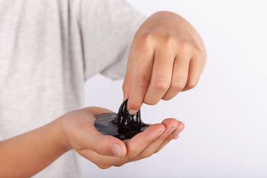 Young boy playing wiht black slime in his hand