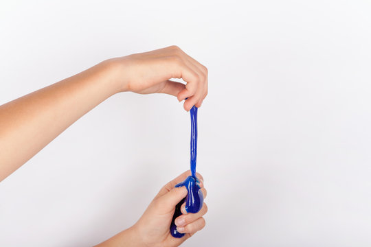 Child hands stretching a blue slime toy like noodles