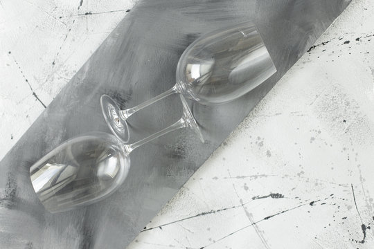 Two large empty glasses lie on a gray stone table