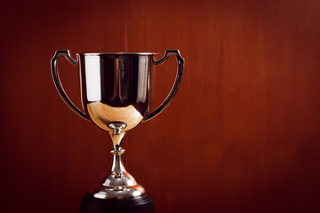 winner concept silver trophy placed on wooden table with background.