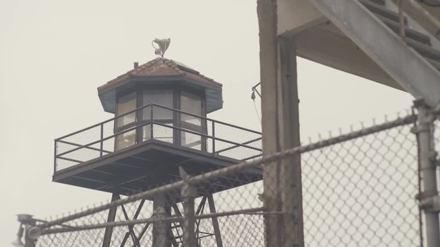San Francisco Bay - Alcatraz island during foggy day - guard tower with fence, dynamic dolly shot