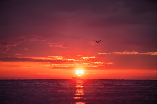Fototapeta July morning. Silhouette of two people in a local small fishing boat moving with sunrise in the background