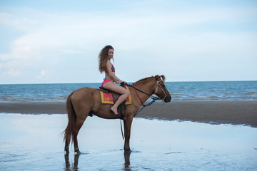 Pretty young lady riding a horse on the beach background of the sea