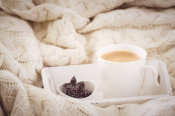 Hot beverage mug with chocolate cookies in a white wool blanket. Hot drink, cozy home and cold...