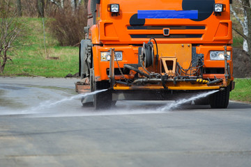 Front view of the orange truck for washing cleaning the road in the park