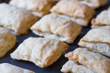 Close up view of a freshly baked pies made of puff pastry on a baking sheet (shallow depth of field)