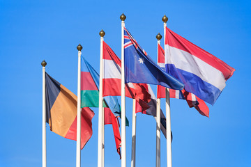 Flags of different countries against a bright blue sky