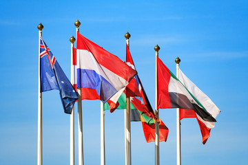 Flags of different countries flutters in the wind a background of blue sky