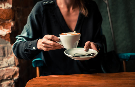 Elegant woman drinking cappuccino at coffee shop. Warm toned filter image