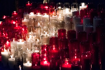 White and red candles lit up in a church, burning brightly