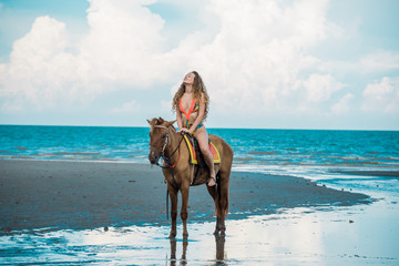 Pretty young lady riding a horse on the beach background of the sea
