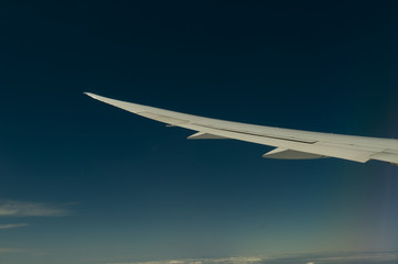Wing of airplane flying above the clouds in the sky