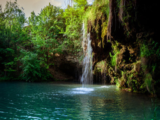 Waterfall and a beautiful lagoon lake for relaxing in the summer forest.