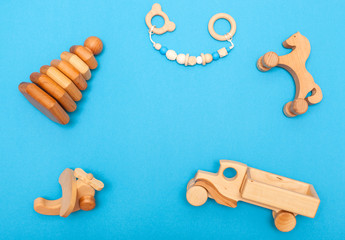 FlatLay Baby Clothes.Wooden children's handmade toys: airplane, car, horse, pyramid, teethers on blue background close-up with place for text. Developing games for the smallest, organic toys
