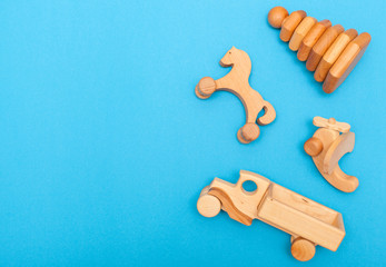 Flat Lay Baby. natural, wooden children's environmental toys handmade: airplane, car, horse, pyramid on a blue background close-up with space for text. Developing games for the smallest boys and girls
