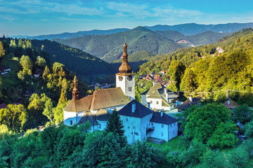 Fototapeta na wymiar Old mining village. Historic church in Spania dolina. Falltime trees at sunrise,Slovakia