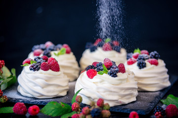 Homemade meringue basis for cake Pavlova with fresh blueberries and BlackBerry and powdered sugar on black  background. Copy space