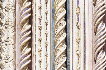 Detail of the facade of the cathedral of Orvieto, Italy. Spiral marble columns decorated with...