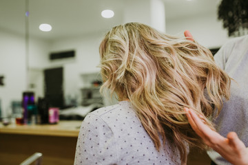 Fototapeta premium Beautiful hairstyle of young woman after dying hair and making highlights in hair salon.