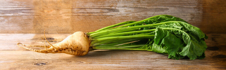 Sugar beet with tops on an old wooden table.