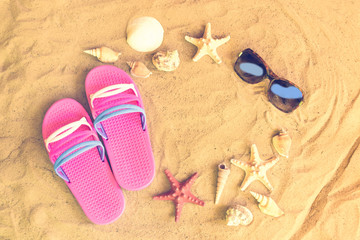 Pink flip fops, sunglasses, starfishes and seashells on sand beach