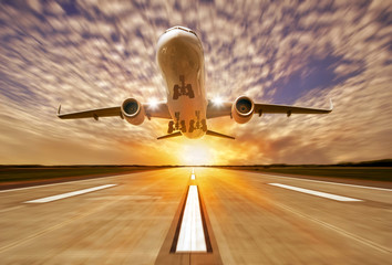 Passenger airplane landing at sunset on a runway