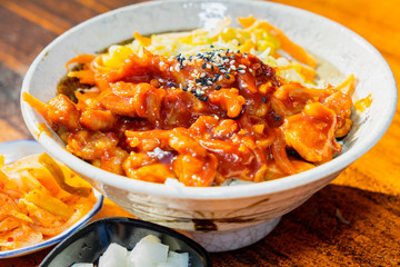 Korean stir fried chicken rice in white bowl on wooden table