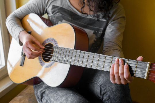 woman's hands playing acoustic guitar, close up