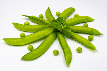 pods of young green peas lined in a circle in a shuffle with green peas on a white background, view from the side