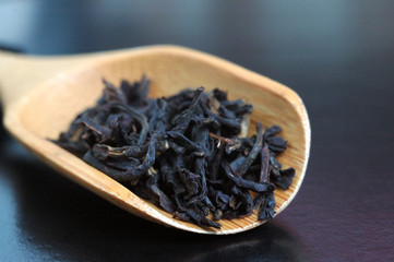 Black English tea in a wooden spoon on the table