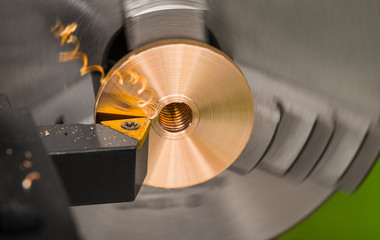 Close-up of a tool bit when turning on a lathe. Bronze product clamped in a rotating chuck of the...