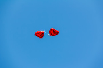 red balloons in the shape of a heart in the blue sky