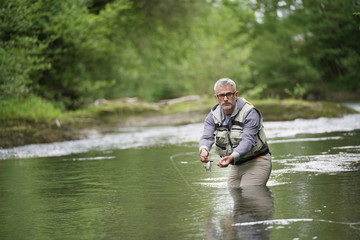 Fisherman fly-fishing in river