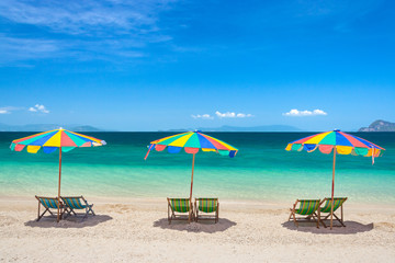 Colorful beach chairs with umbrellas on a sunny day.